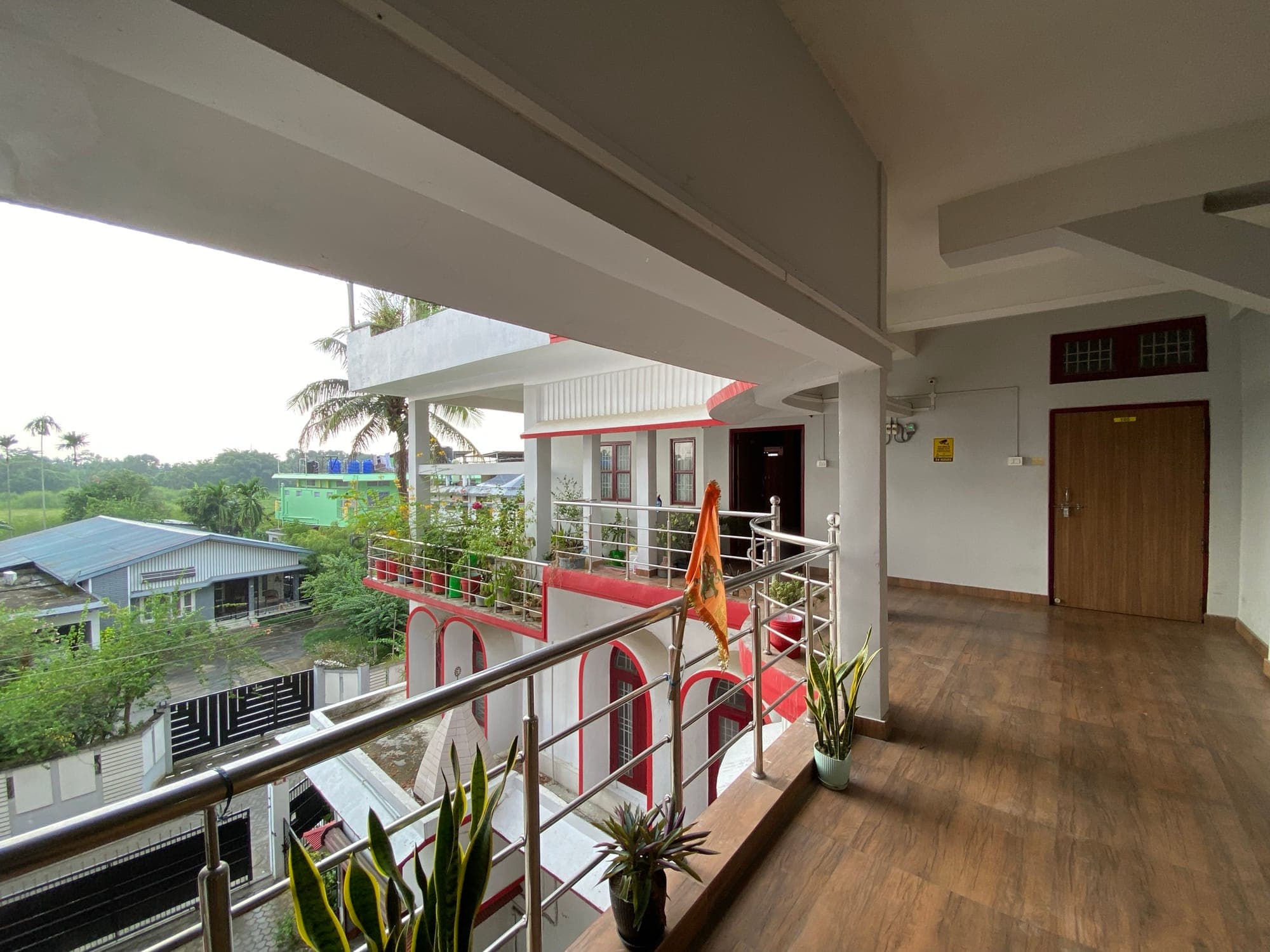 Open balcony corridor with wooden floors and potted plants